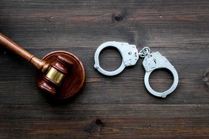 Judge's gavel and metal handcuffs on wooden table