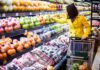 Woman in a yellow coat shopping for fruits in a supermarket