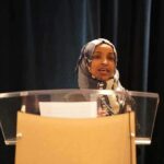 Deportation Showdown: Trump Targets Omar Woman in hijab speaking at a podium