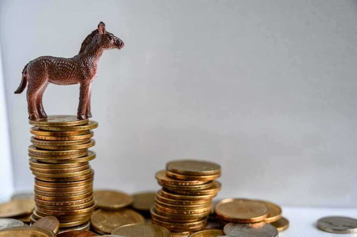 shutterstock_1442990687 Plastic donkey figurine on a stack of coins