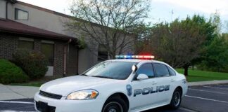 Police car with flashing lights parked outside a building