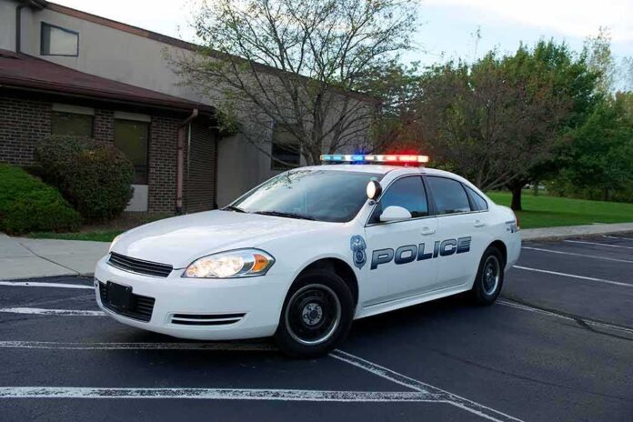 shutterstock_160872062 Police car with flashing lights parked outside a building