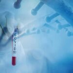 Fauci Texts Put Vaccine Messaging Under Scrutiny Gloved hand holding a COVID-19 test tube beside a stylized DNA helix
