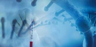 Gloved hand holding a COVID-19 test tube beside a stylized DNA helix
