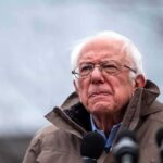 Sanders Moves To Stall Data Centers elderly man in glasses speaking outdoors into microphones