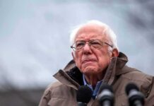 Sanders Moves To Stall Data Centers elderly man in glasses speaking outdoors into microphones