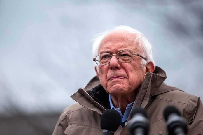 elderly man in glasses speaking outdoors into microphones