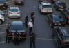 Police officers secure a street with patrol cars and yellow tape