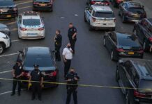 Police officers secure a street with patrol cars and yellow tape