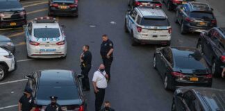 Police officers secure a street with patrol cars and yellow tape