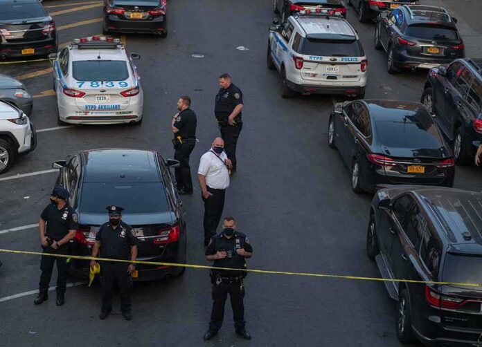 shutterstock_1976471639 Police officers secure a street with patrol cars and yellow tape