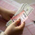 Old-School Scam Hits NYC Again Hands holding lottery tickets and U.S. dollar bills
