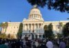Crowd gathers before a neoclassical capitol building with dome
