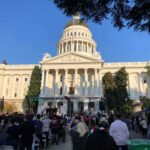 City Hall’s 9-0 Vote Ignites Budget War Crowd gathers before a neoclassical capitol building with dome