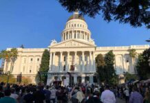 City Hall’s 9-0 Vote Ignites Budget War Crowd gathers before a neoclassical capitol building with dome