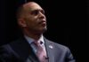 Progressive Upset Scrambles Midterms man in suit looking to the side on a dark stage