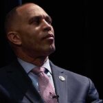 Progressive Upset Scrambles Midterms man in suit looking to the side on a dark stage