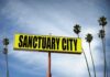 Sanctuary Over? Blakeman Drops Hammer Yellow roadside sign reading Sanctuary City with palm trees