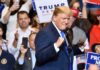 Donald Trump at a rally raising his fists on stage