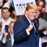 Donald Trump at a rally raising his fists on stage