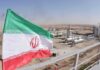 Iran flag over an oil and gas facility in a desert landscape
