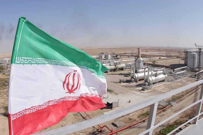 Iran flag over an oil and gas facility in a desert landscape
