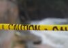 Yellow caution tape stretched across a blurred outdoor scene