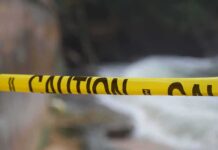 Yellow caution tape stretched across a blurred outdoor scene
