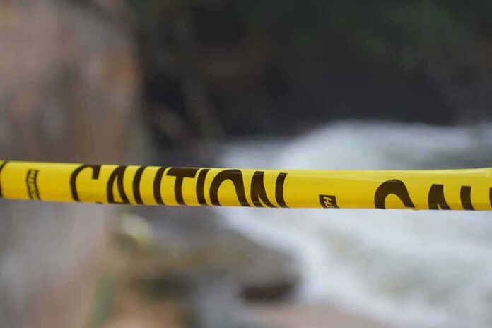 Yellow caution tape stretched across a blurred outdoor scene