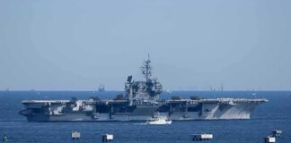 Aircraft carrier at sea with small boat alongside