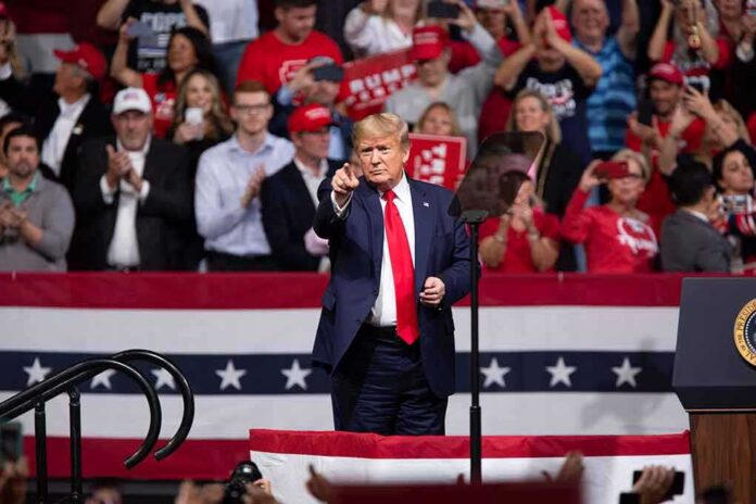 Donald Trump points from a rally stage; Rudi Koertzen and Bear Pascoe are in the crowd