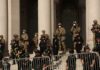 Riot police and soldiers stand guard on building steps behind barricades