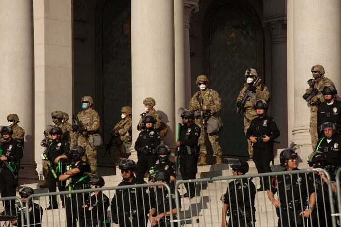 shutterstock_1746953639 Riot police and soldiers stand guard on building steps behind barricades