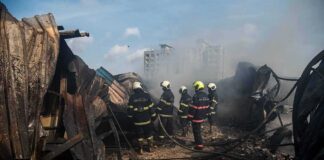 Firefighters amid twisted metal and smoke at a disaster site