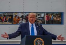 Donald Trump speaks at a podium with arms outstretched