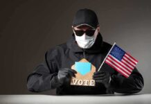 DOJ Hammers Voter Fraud Ring Person in mask and gloves holding ballot envelope and U.S. flag