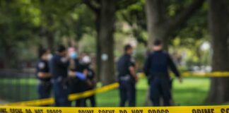 crime scene tape with police officers in a park