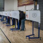 First Votes In – Shock Coming Next? Voters at polling booths in a gymnasium