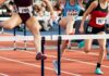 Female athletes clearing hurdles on a track
