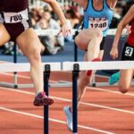 Female athletes clearing hurdles on a track