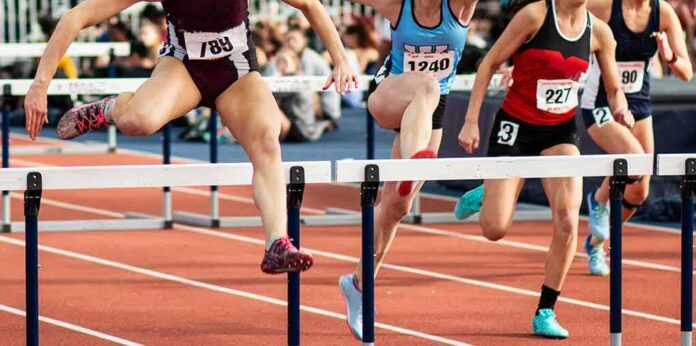 Female athletes clearing hurdles on a track