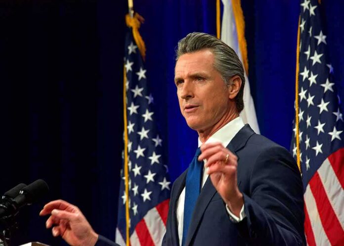 shutterstock_2135008825 Man in suit speaking at podium with U.S. flags behind him