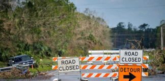 Road closed barricades blocking a flooded rural highway with detour sign