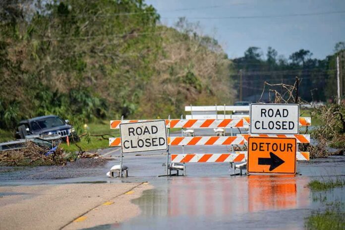 Road closed barricades blocking a flooded rural highway with detour sign