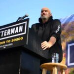 Speaker at outdoor rally standing at podium with microphone