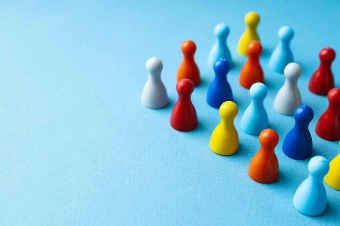 shutterstock_2229311211 Colorful board game pawns grouped on a blue surface