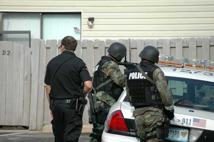 police officers in tactical gear beside patrol car