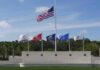 Pentagon Ceremony Honors 9/11 Victims United States flag at half-mast above military branch flags at a memorial