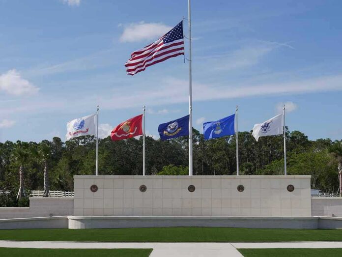 shutterstock_765364459 United States flag at half-mast above military branch flags at a memorial