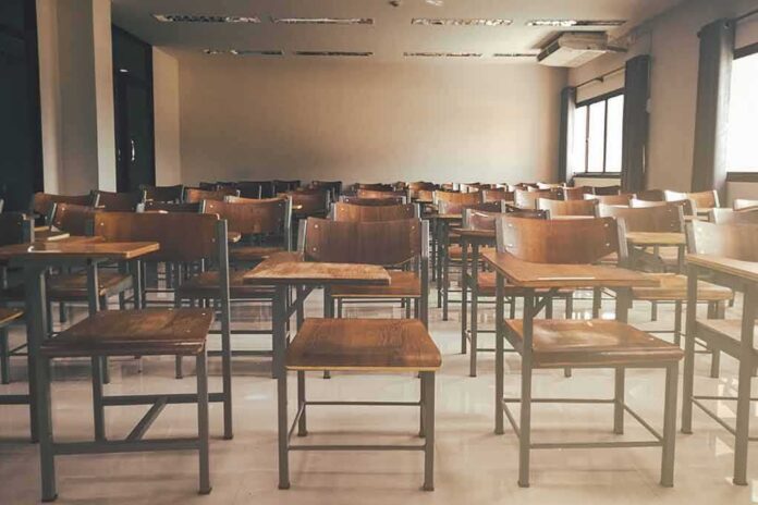 shutterstock_1019829787-1 Empty classroom with rows of wooden desks and chairs